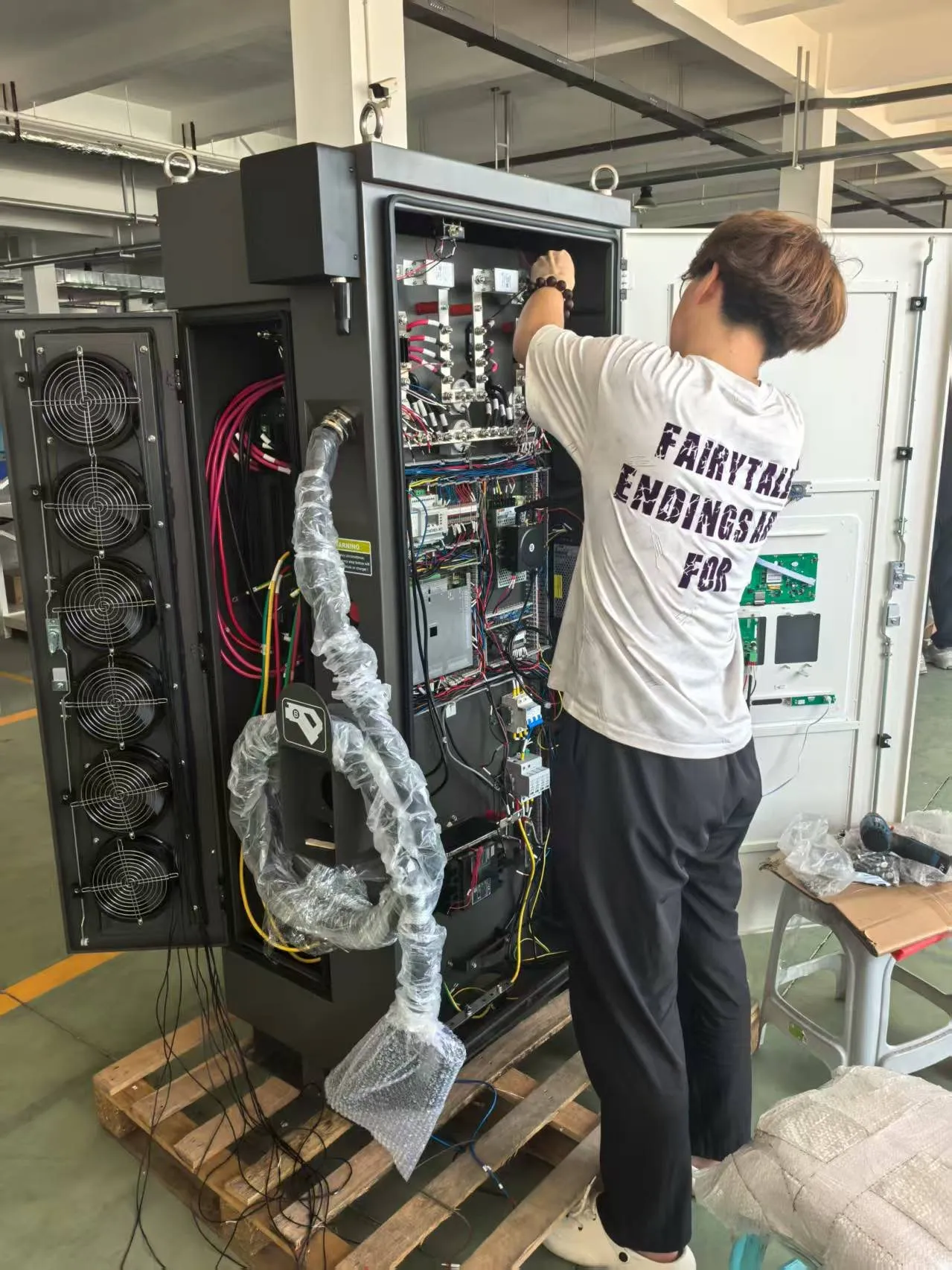 Technician wiring a DC fast charger cabinet